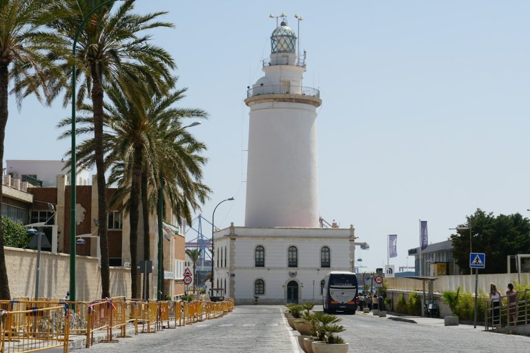 A white light house sitting on the side of a road